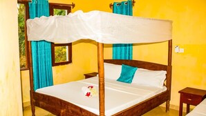 Una cama con dosel, un cojín turquesa y una colcha blanca.