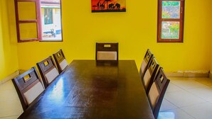 Un comedor con una mesa larga y sillas, un cuadro en la pared y ventanas con vistas a follaje.