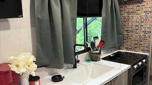 Een compacte keuken met een wit marmeren aanrecht, een inbouwfornuis en een spoelbak.