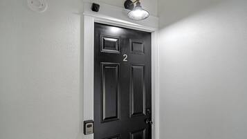 A black door with the number 2, a light fixture above it, and a wall-mounted intercom.