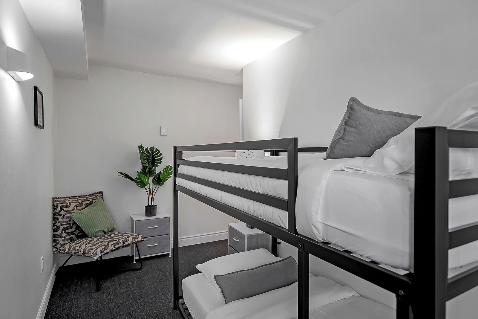 A bunk bed room with a small desk, chair, and a potted plant.