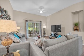 Ein Wohnzimmer mit einer Sofagarnitur, einem Fernseher und einem Deckenventilator.