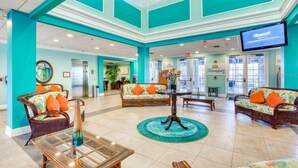 Een hal met rieten meubels, een glazen salontafel en een muur in turquoise.