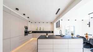 A modern kitchen with a central island, built-in appliances, and a dining area with a table and chairs. - Sumptuous Villa - AC- 6br- 12p- Cannes (Cannes)