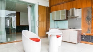 A modern kitchen with white cabinets, a stainless steel range hood, and a glass door leading to a bathroom. - Hi Quality Dago by My Hospitality (Coblong)