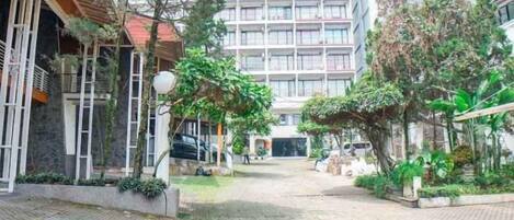 A courtyard with a paved walkway, surrounded by buildings and greenery.