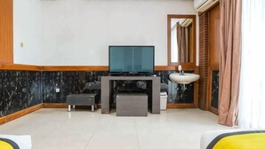 A hotel room with a TV, a small table with a lamp, a sofa, and a window with curtains. - Hi Quality Dago by My Hospitality (Coblong)