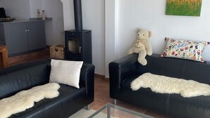 Una sala de estar con dos sofás de cuero negro, una mesa de centro de vidrio, una chimenea y un cuadro en la pared.
