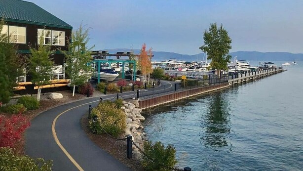Une propriété située au bord de l’eau, dotée d’une promenade pavée, d’un quai et d’une marina en arrière-plan.
