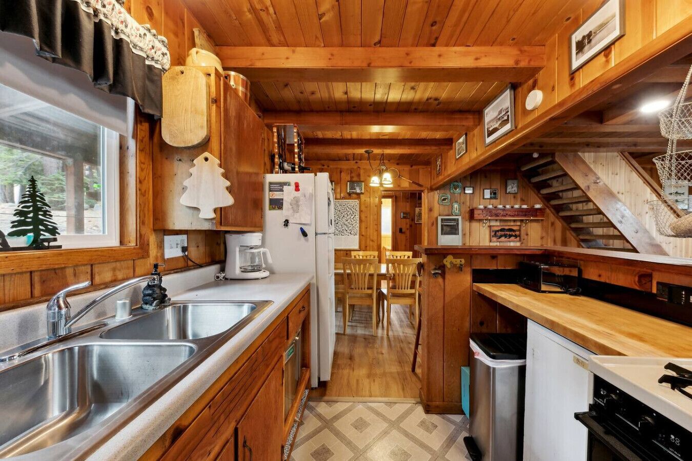 Eine holzverkleidete Küchenzeile mit Kochinsel, Kühlschrank, Kaffeemaschine und Spüle.