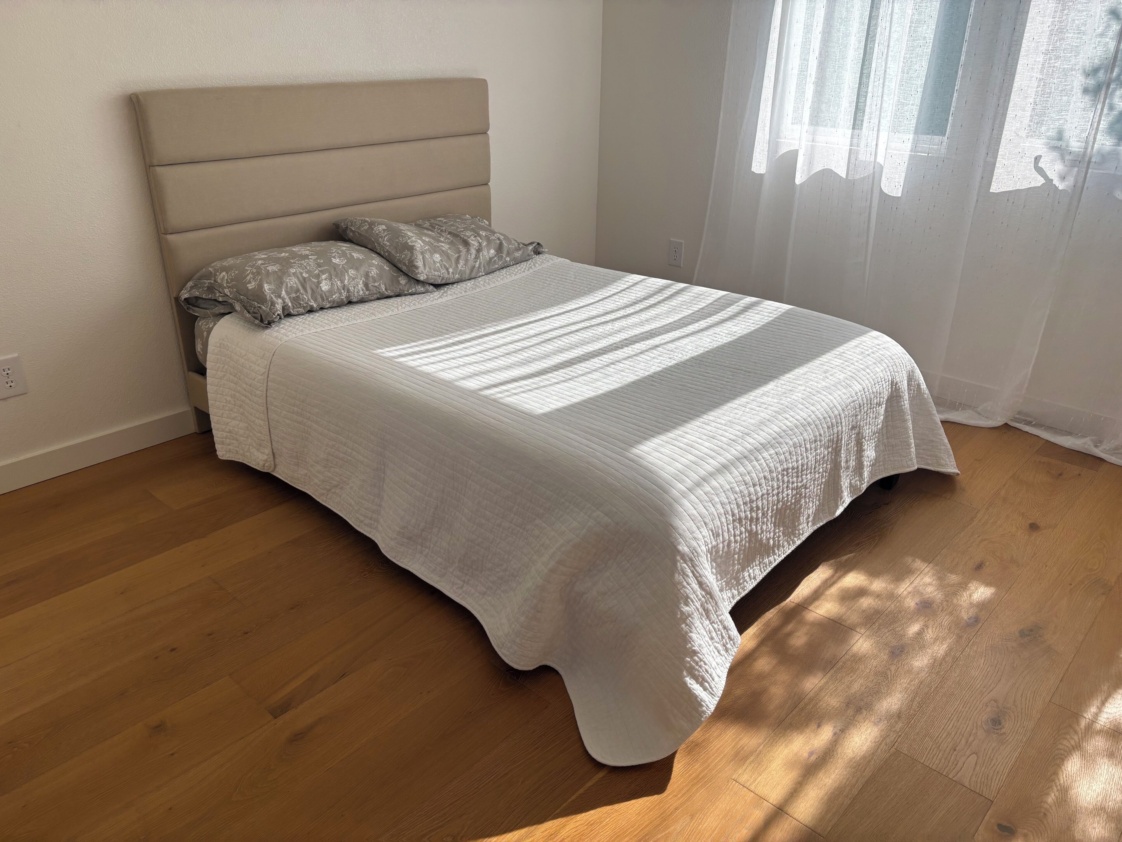 Una cama con cabecera, una colcha acolchada y dos almohadas.