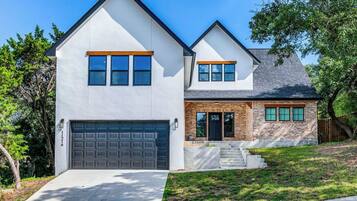 A two-story house with a garage, a brick section, and a front yard.