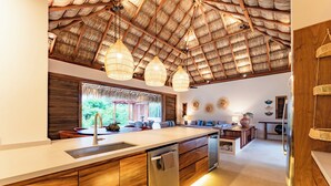 Een moderne keuken met een groot eiland, houten kastjes en een rieten plafond.