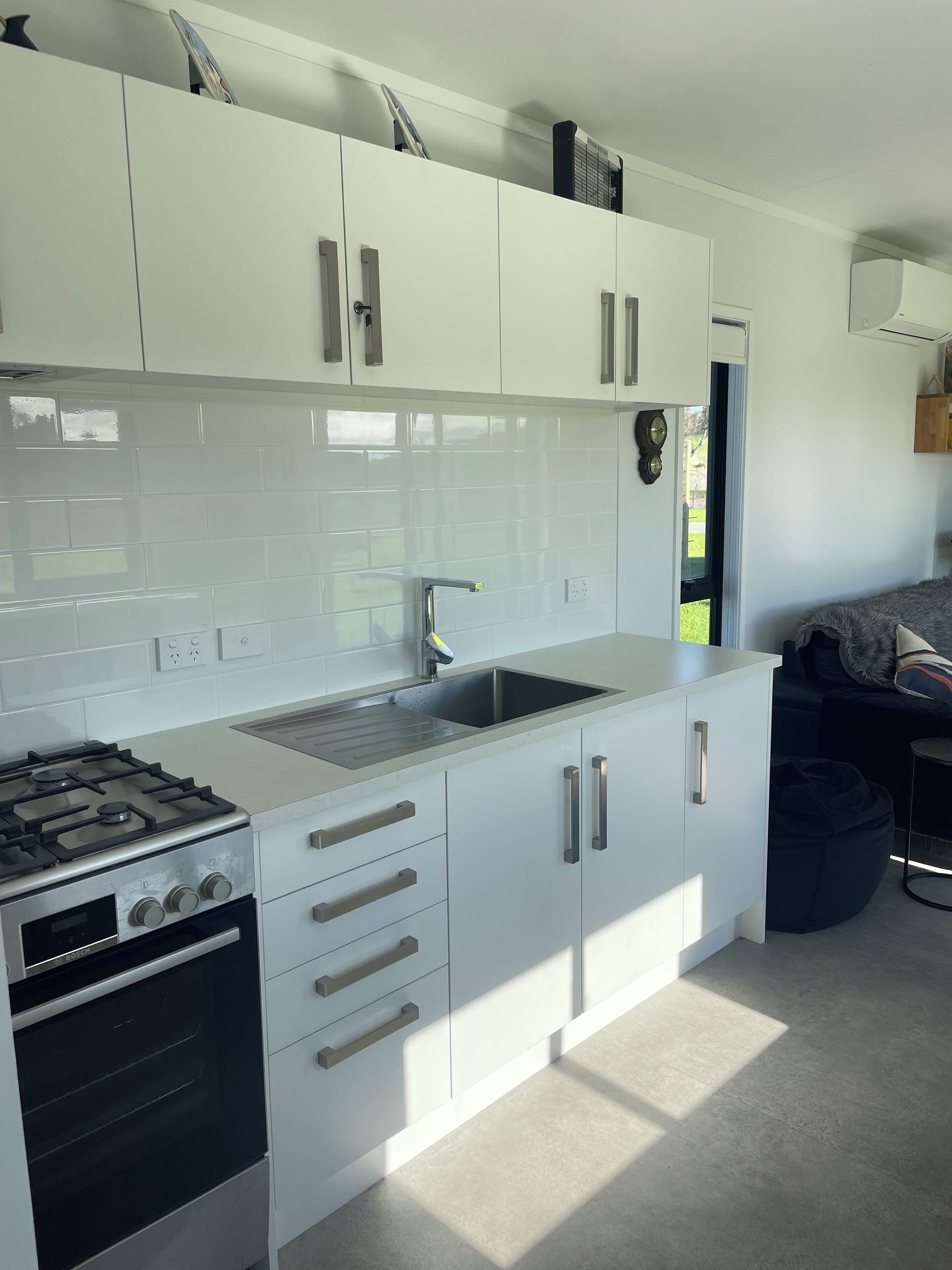 Una cucina moderna con pensili bianchi, un lavello in acciaio inossidabile e un forno integrato.
