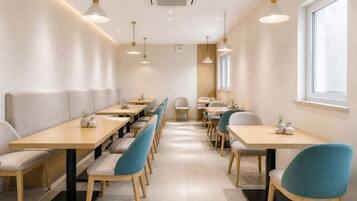 A modern dining area with long tables and chairs, a window, and pendant lighting.