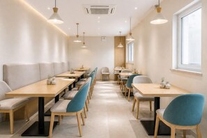A modern dining area with long tables and chairs, a window, and pendant lighting. - Yijia Hotel (Xinyi Railway Station Nanjing Road) (Xinyi)