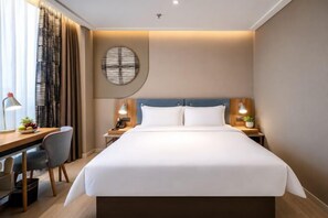 Habitación de hotel con una cama grande, un escritorio, una silla y un adorno circular en la pared.