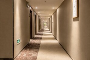 Un pasillo de hotel con puertas a ambos lados, una alfombra estampada y un piso de color claro.