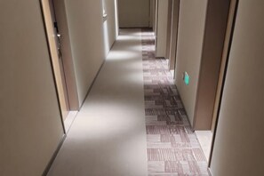 A hallway with patterned flooring, doors on both sides, and a light switch on the wall.