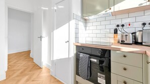 A modern kitchen with white cabinets, a wooden countertop, and a built-in oven.