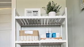 A bathroom with a toilet, a shelf with toiletry items, and a sign above the shelf.