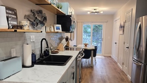 A modern kitchen with a marble countertop, stainless steel appliances, and a wooden floor.