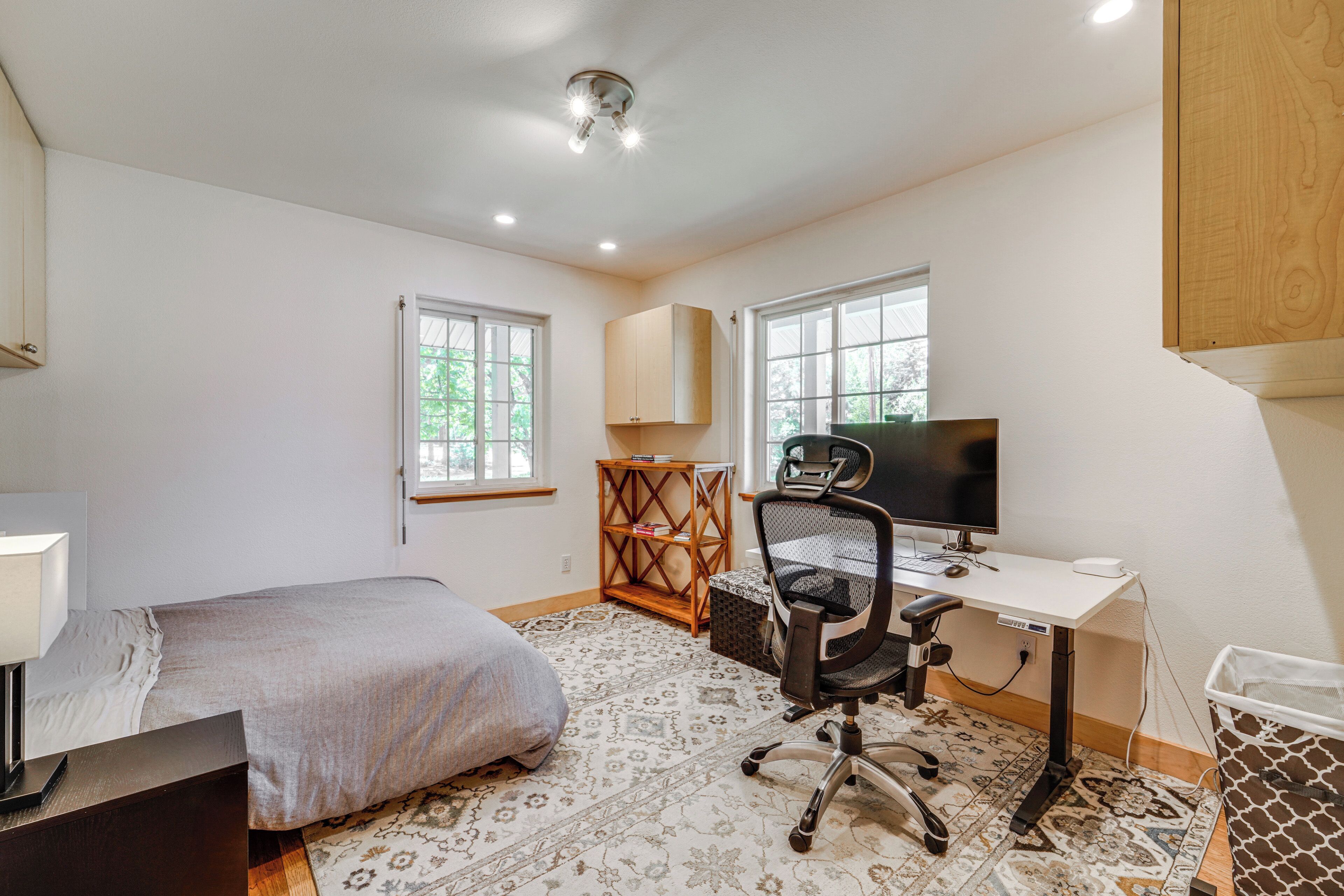 A bedroom with a bed, desk, chair, and a window.