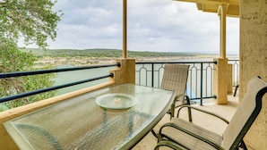A balcony with a glass table and chairs, overlooking a body of water and greenery. - Community Perks: Scenic Lake Travis Getaway! (Lago Vista)