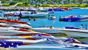 Un puerto deportivo con numerosas embarcaciones amarradas, rodeado de edificios altos y palmeras.