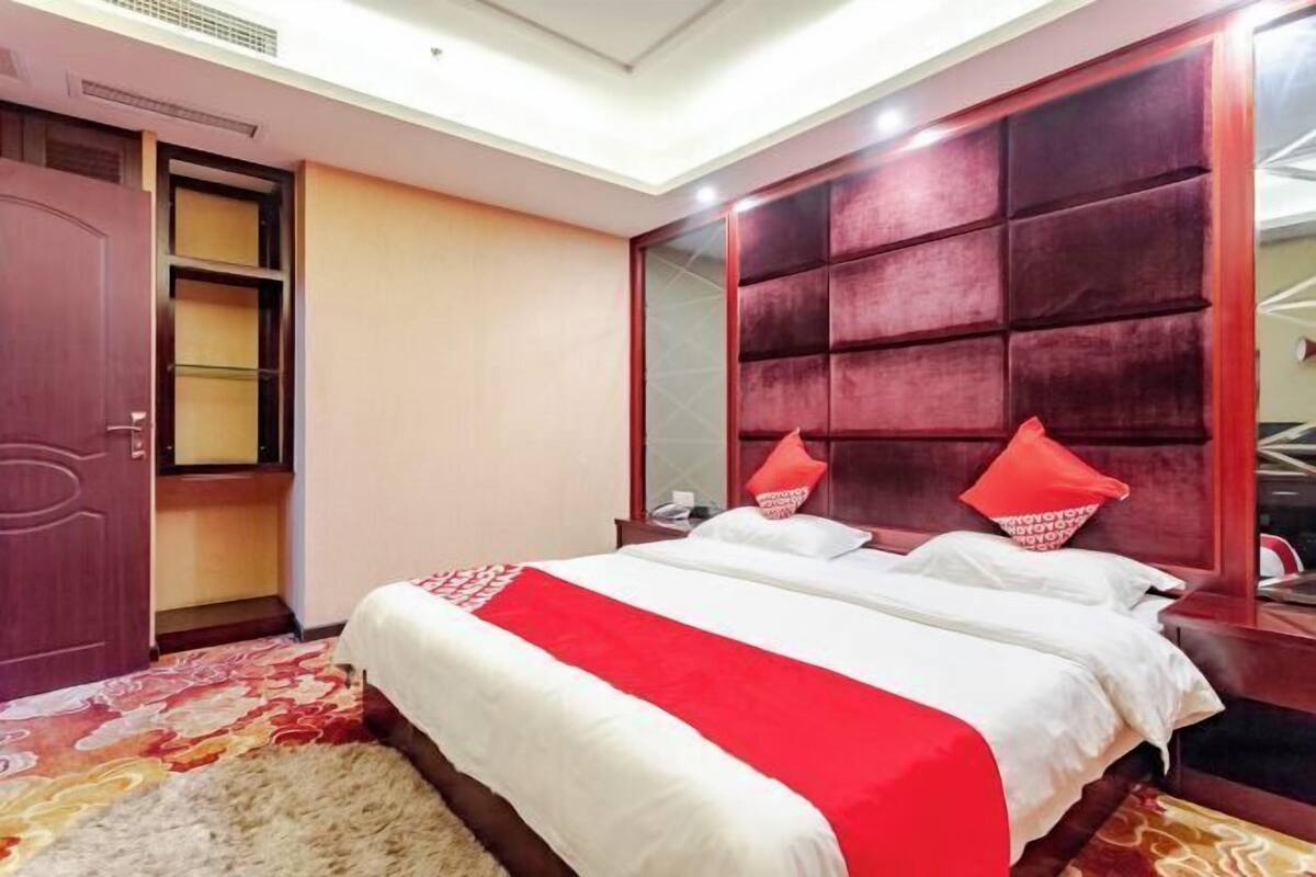 Een hotelkamer met een groot bed, een garderobe en een rode accentmuur.