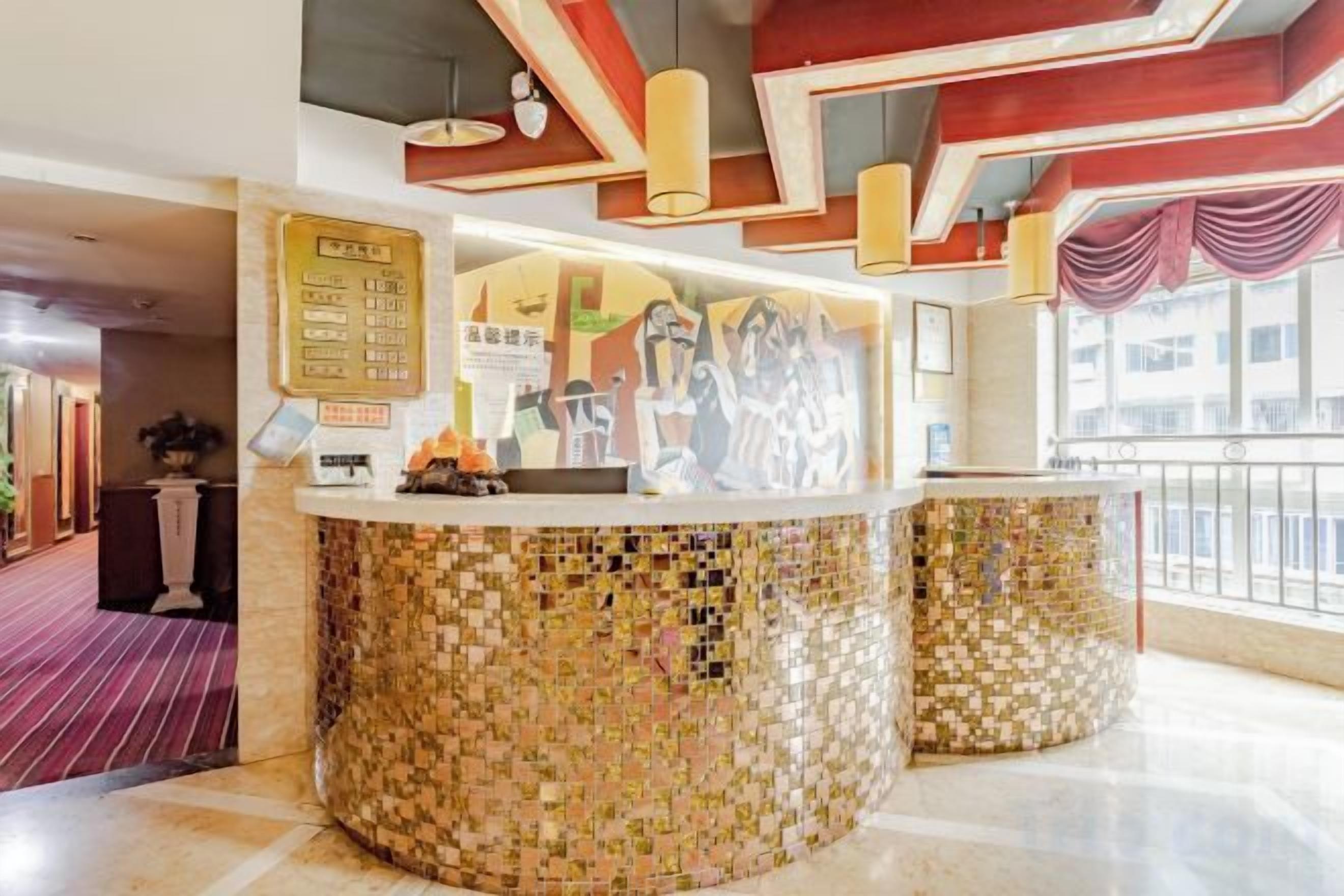 Zona de recepción con mostrador de mosaicos, un tablón de anuncios con información y vistas al exterior.