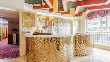 Zona de recepción con mostrador de mosaicos, un tablón de anuncios con información y vistas al exterior.