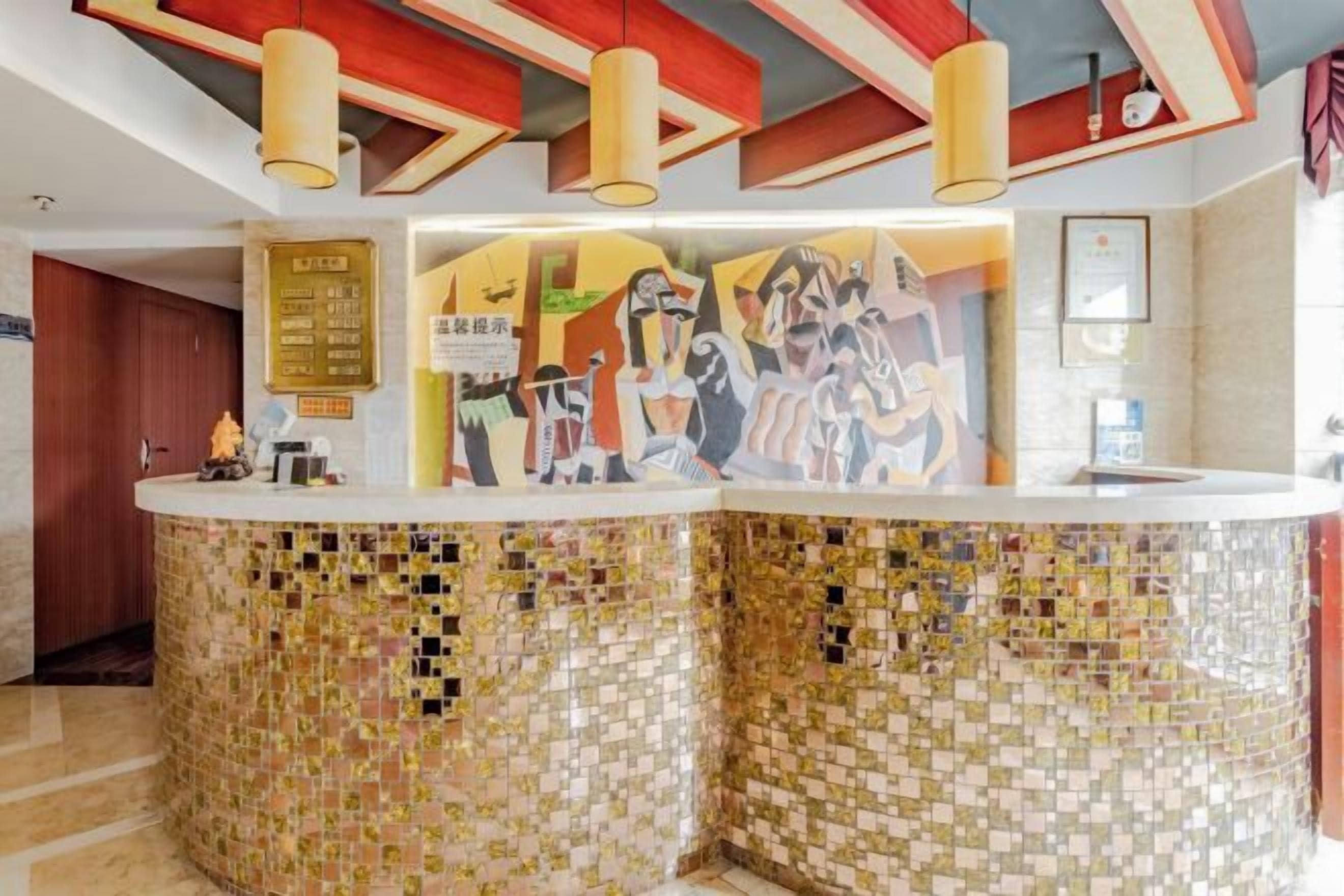 A reception area with a mosaic-tiled counter, a wall with abstract art, and a ceiling with geometric patterns.
