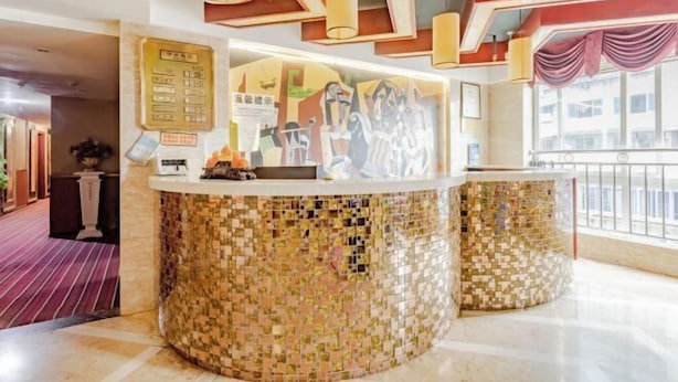 Un área de recepción con mostrador de mosaicos, un tablón de anuncios y vistas al exterior a través de amplias ventanas.
