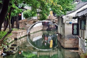 Een klassieke gracht met een stenen brug, boten en gebouwen met traditionele architectuur.