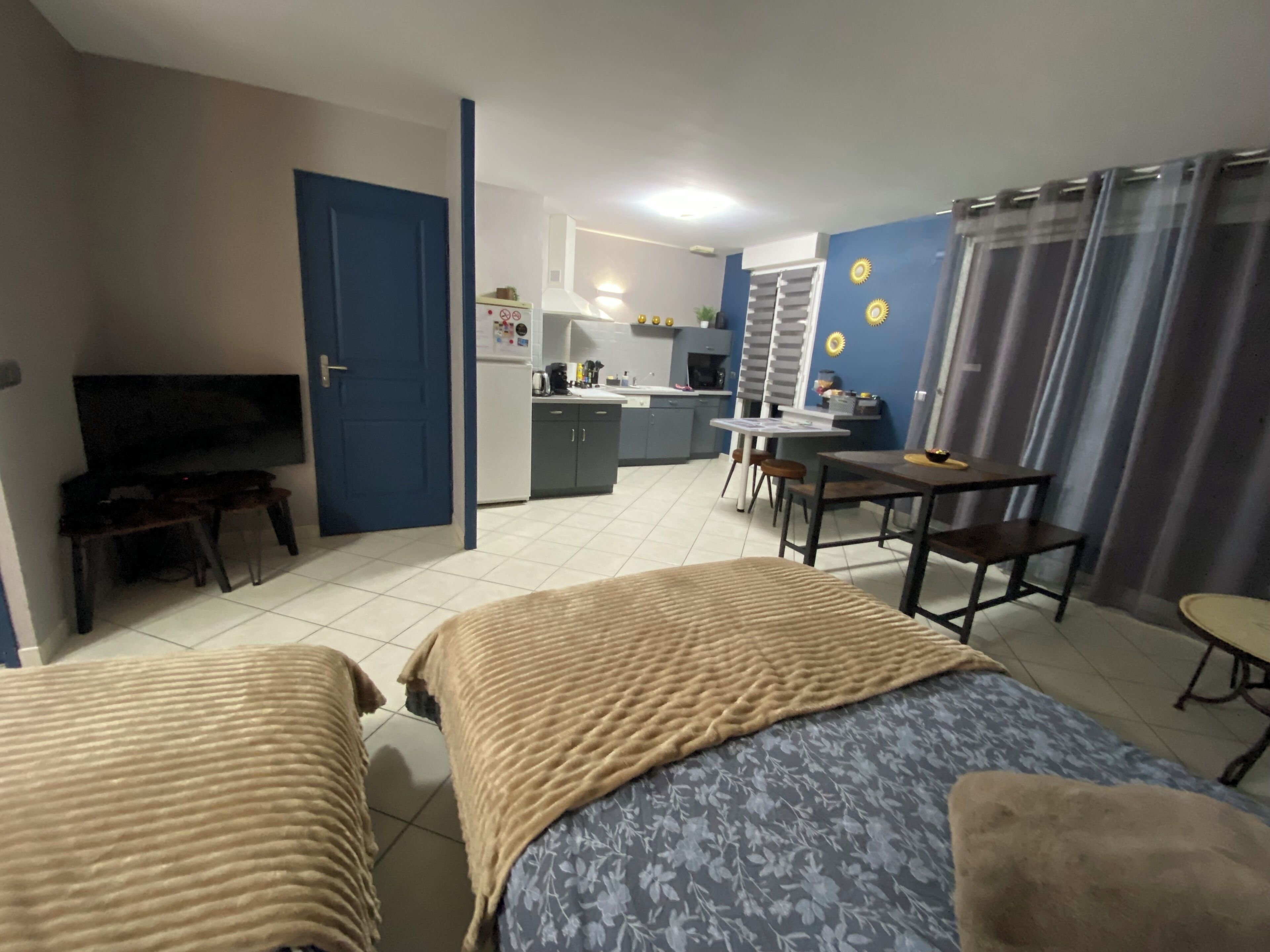 Una habitación de hotel con dos camas, televisión, kitchenette y zona de comedor.