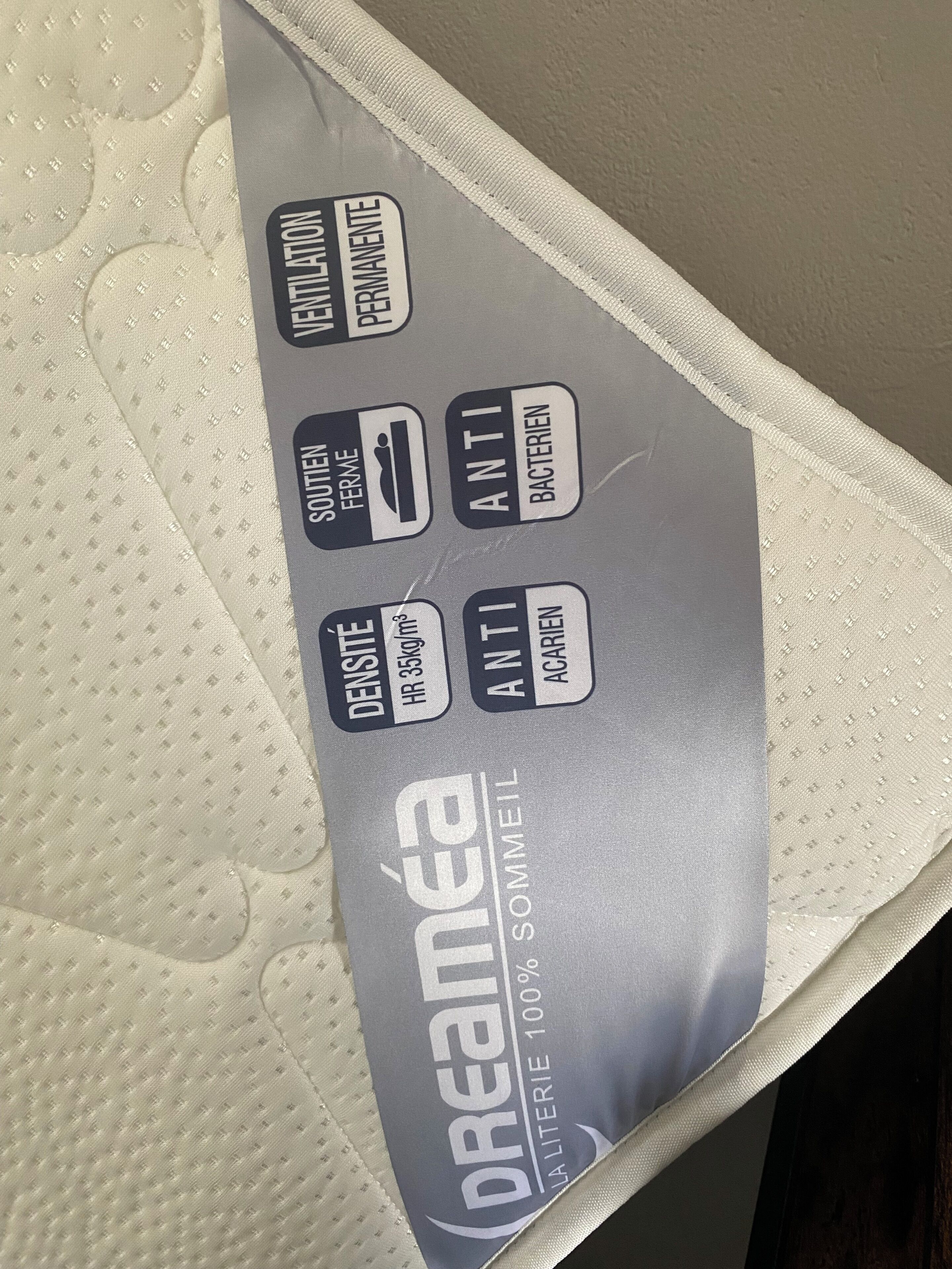 Une étiquette de matelas indiquant les caractéristiques suivantes : ventilation, propriétés antibactériennes et densité.