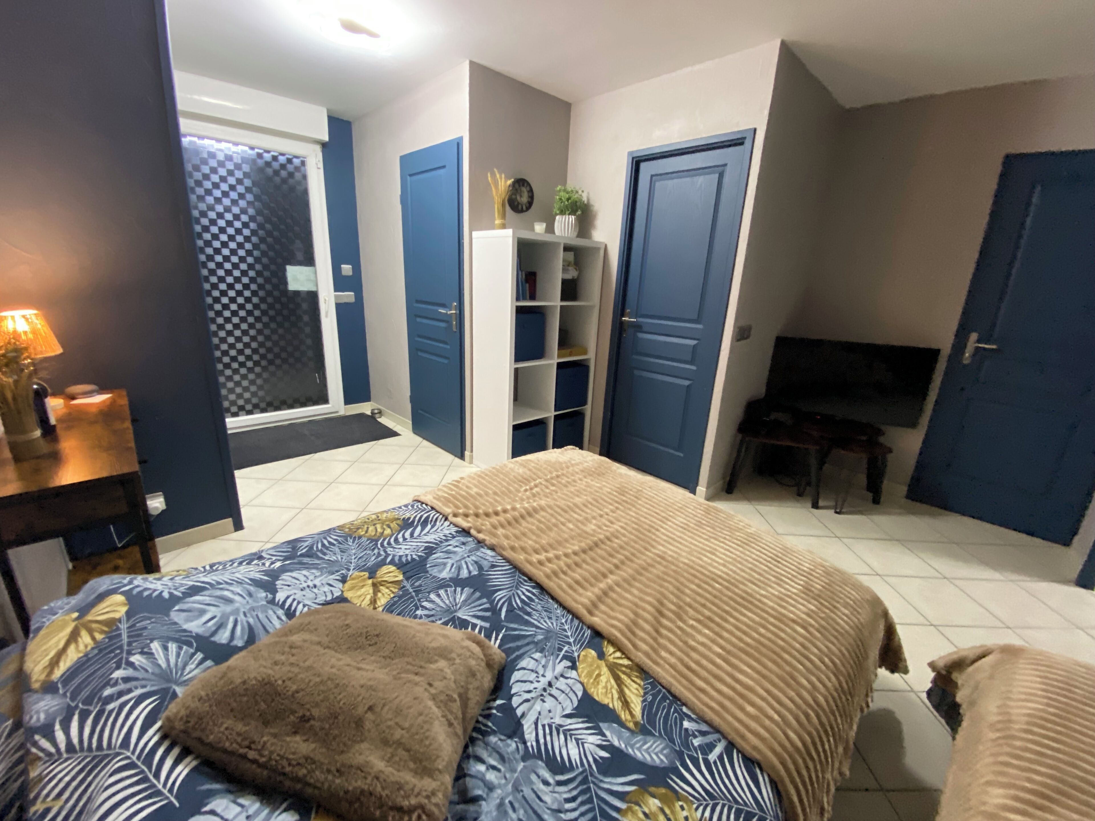 A bedroom with a bed, a desk, a chair, and a TV.