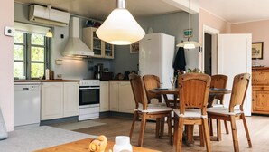 A modern kitchen with white cabinets, a dining table with wooden chairs, and pendant lighting.