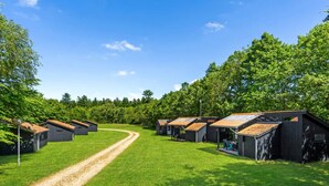 En campingplads med flere hytter, en grussti og frodig vegetation.