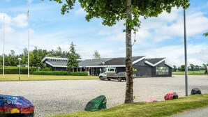 A gravel parking area with a building in the background, a truck, and a tree.