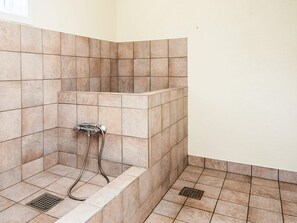 A corner shower with beige tiles, a showerhead, and a drain. - 4 Person Holiday Home in Hampen (Hampen)