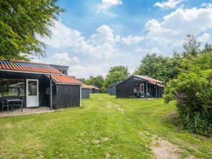 A row of cabins with a grassy yard and trees in the background.