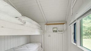 A bunk bed room with white bedding, a small window, and a thermostat on the wall.