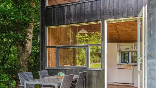 A rustic wooden building with a dining area featuring a table and chairs.