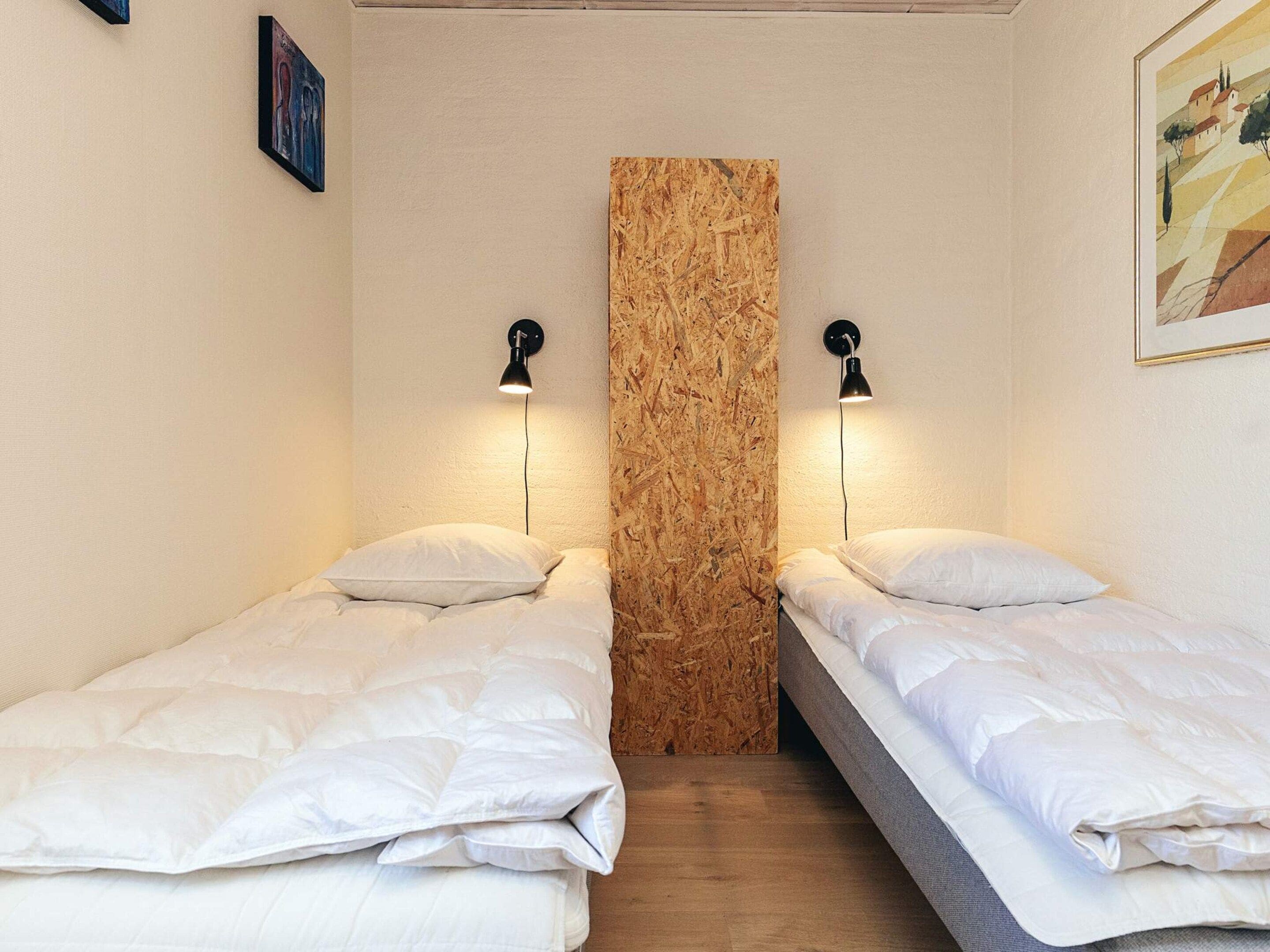 Una habitación con dos camas individuales, una pared de acento de madera y dos lámparas de pared.