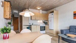 A modern kitchen with wooden cabinets, a dining table, and a gray sofa. - 4 Person Holiday Home in Vestervig (Vestervig)