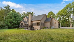 A two-story house with a large front deck, a chimney, and a well-maintained lawn. - Ultimate Group Stay, Pickelball, H/Tub, Fire Pit (Lake Harmony)