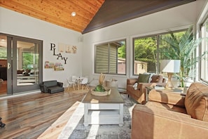 A spacious living room with a wooden ceiling, large windows, and a cozy seating area.