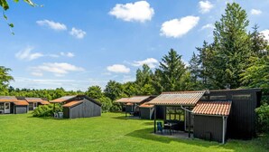 A campground with several cabins, each with a tiled roof and surrounded by grass.